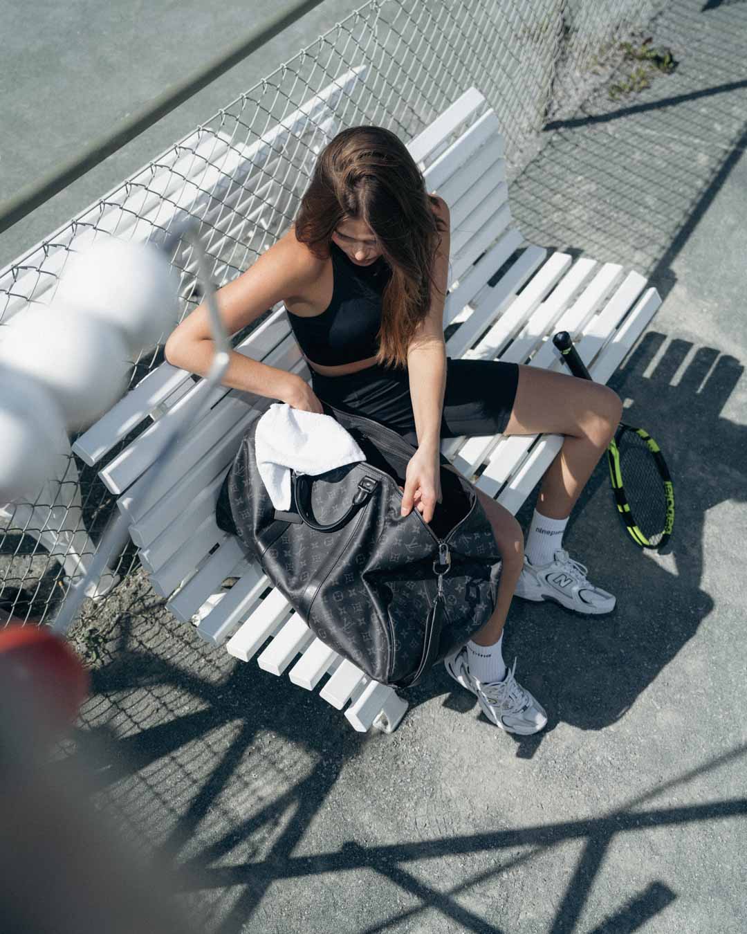 Woman sitting court side looking through her duffle bag